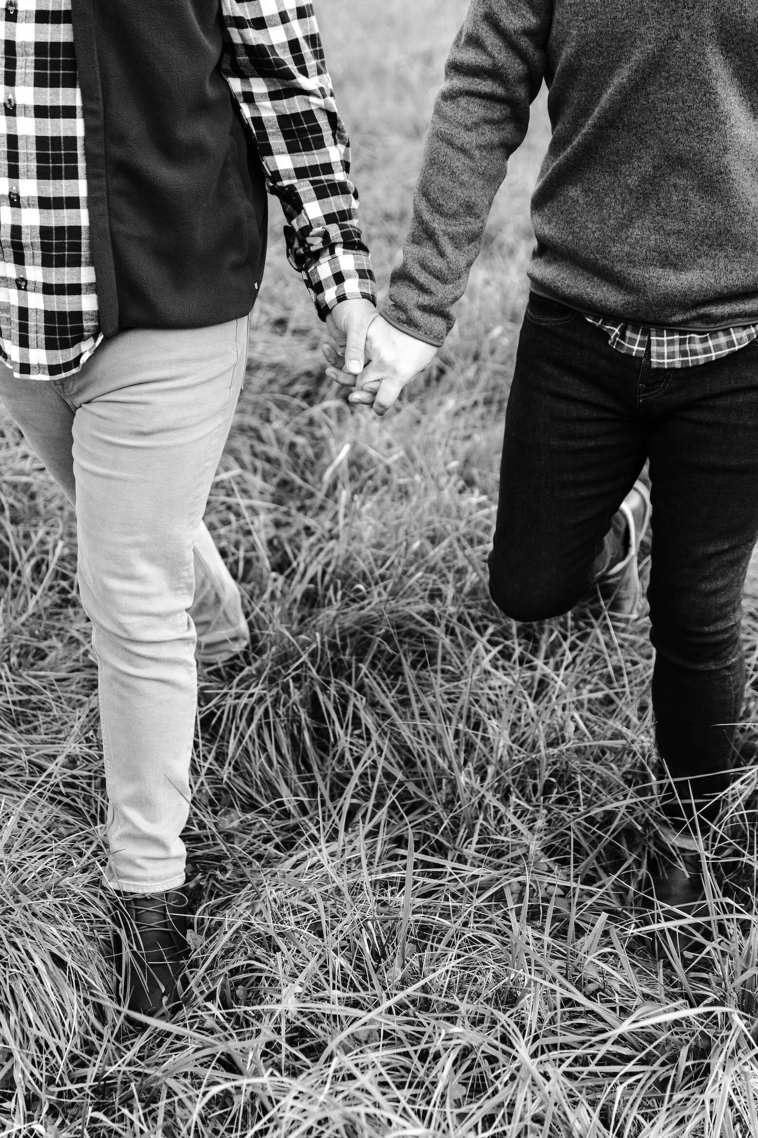 black and white photo of men holding hands in field