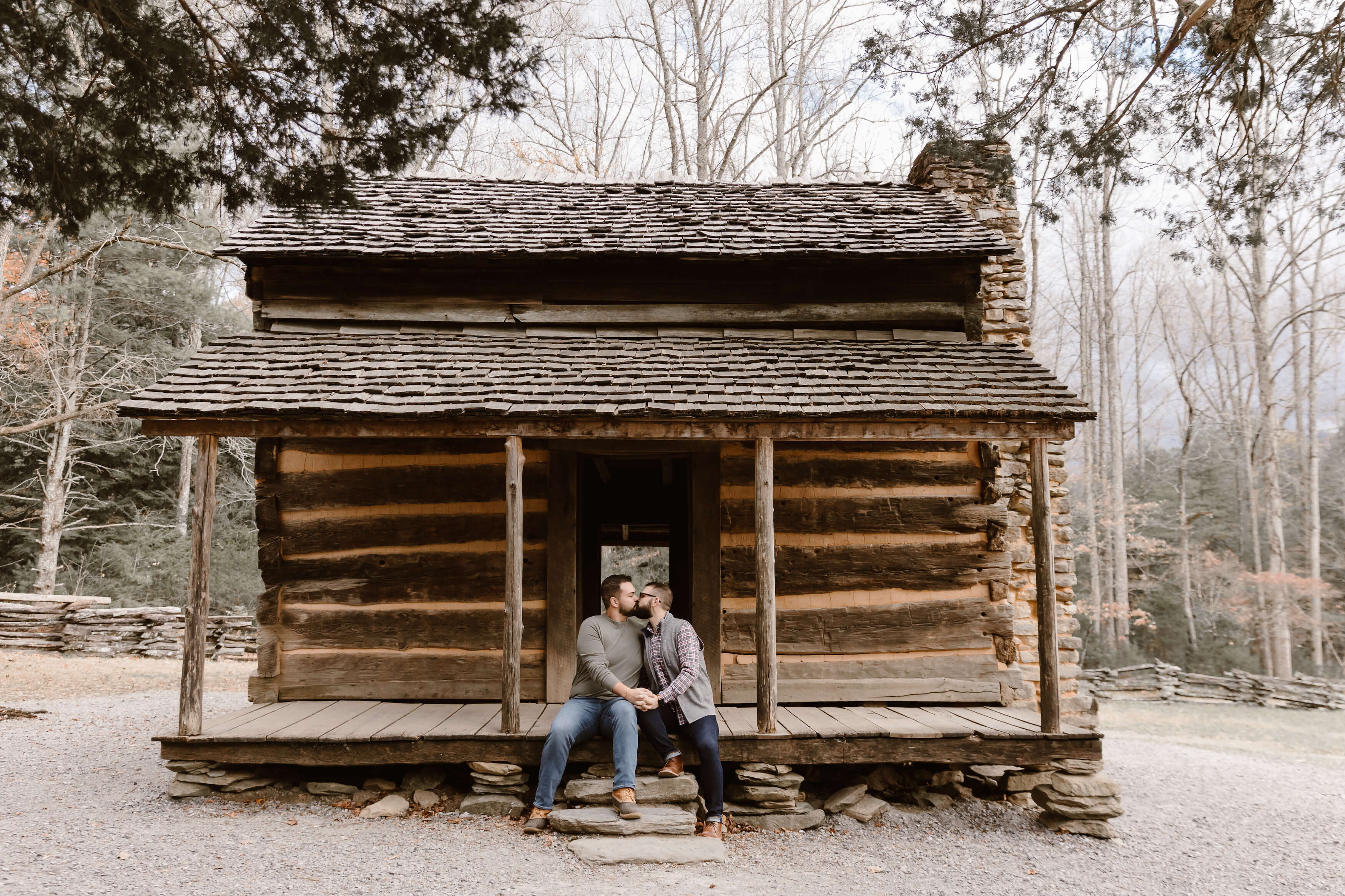two men kissing while sitting on front porch of old cabin