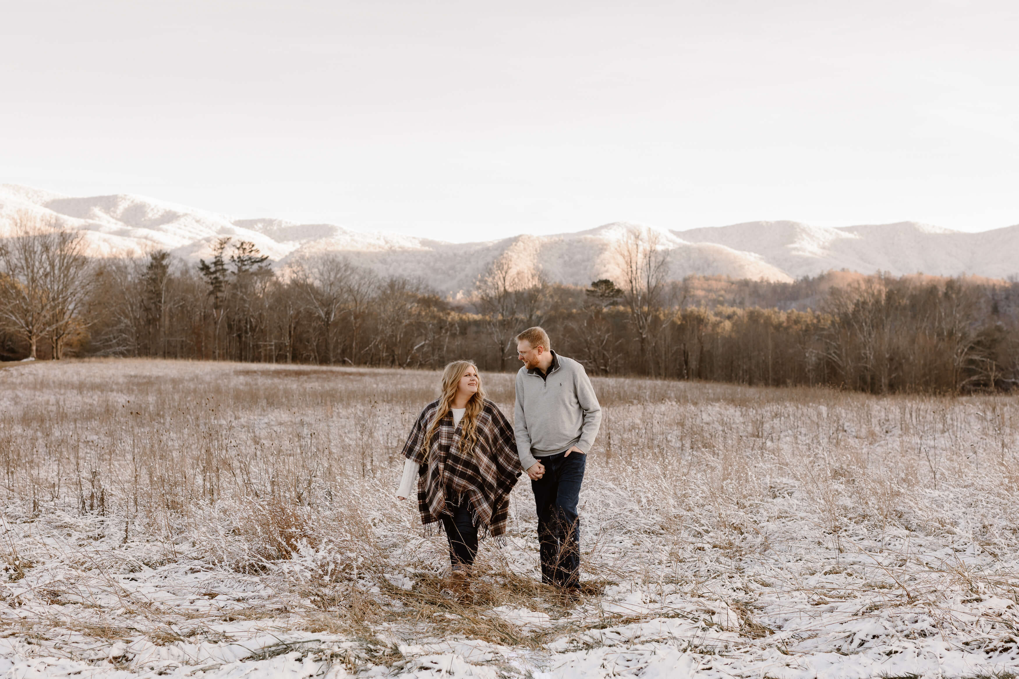 man and woman walking in the snow with the Smoky Mountains behind them