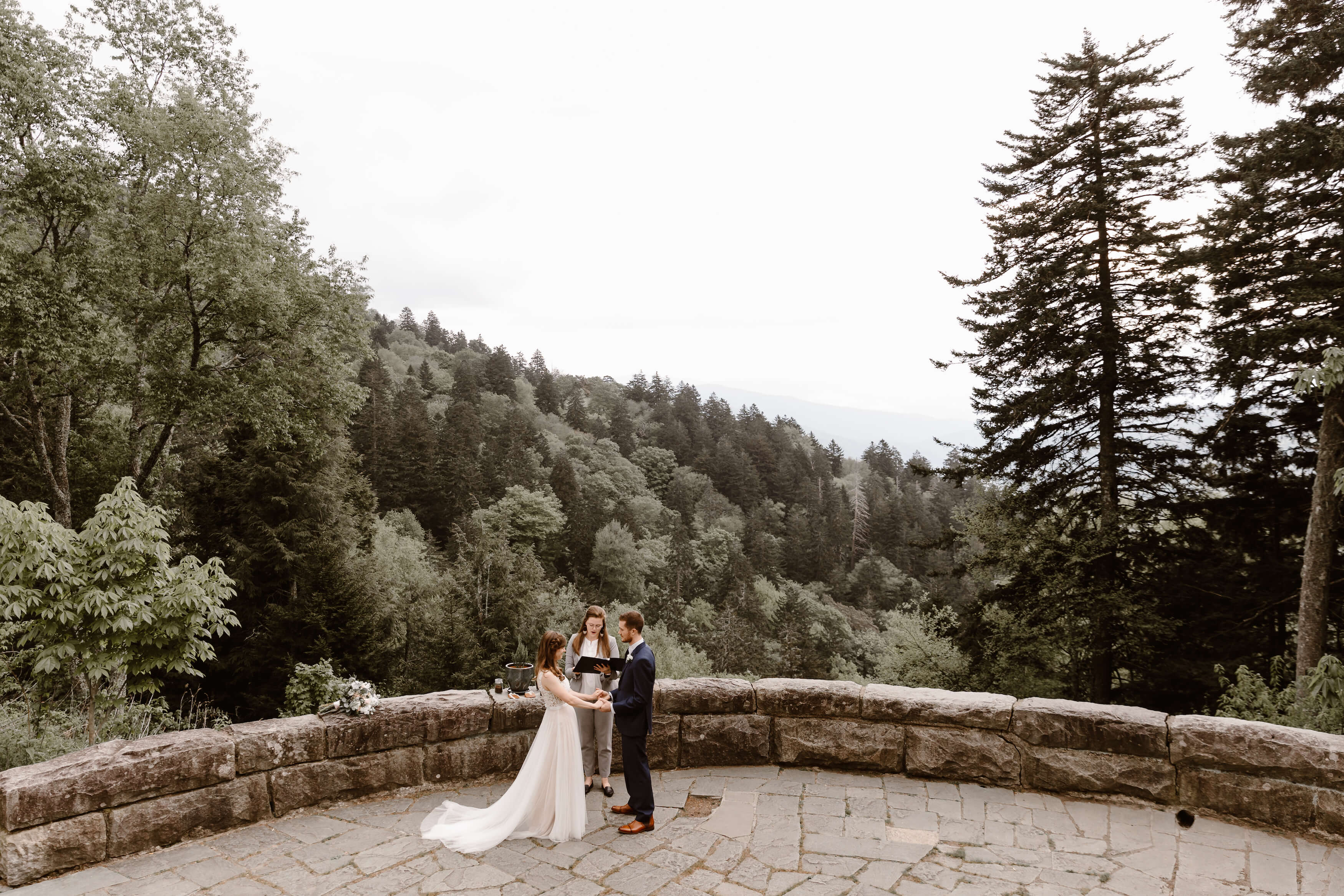 man and woman reading vows on large stone patio over mountains