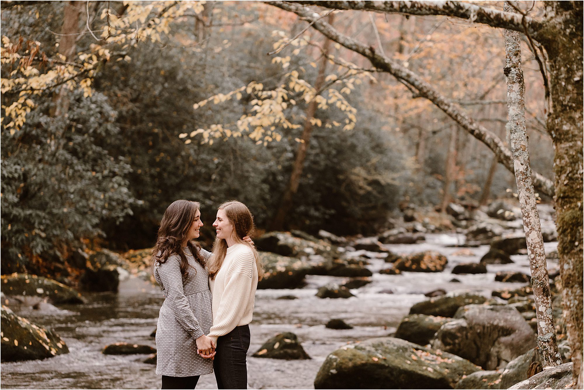 woman and woman holding hands facing each other while standing near river