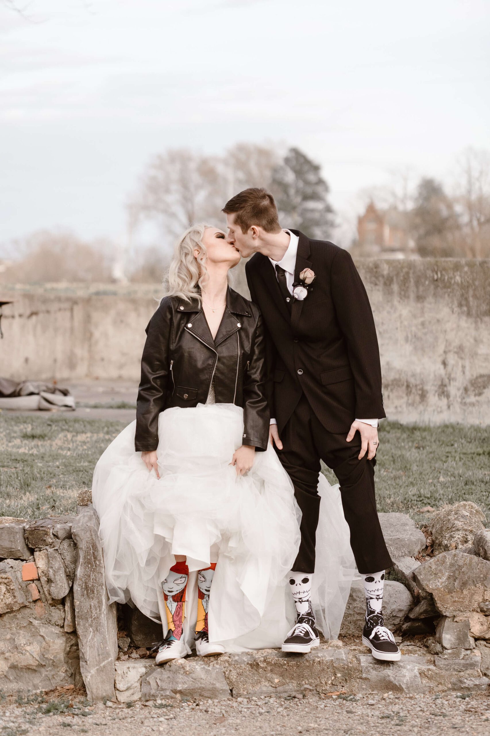 bride and groom showing off wedding socks while wearing leather jacket photographed by Erin Morrison