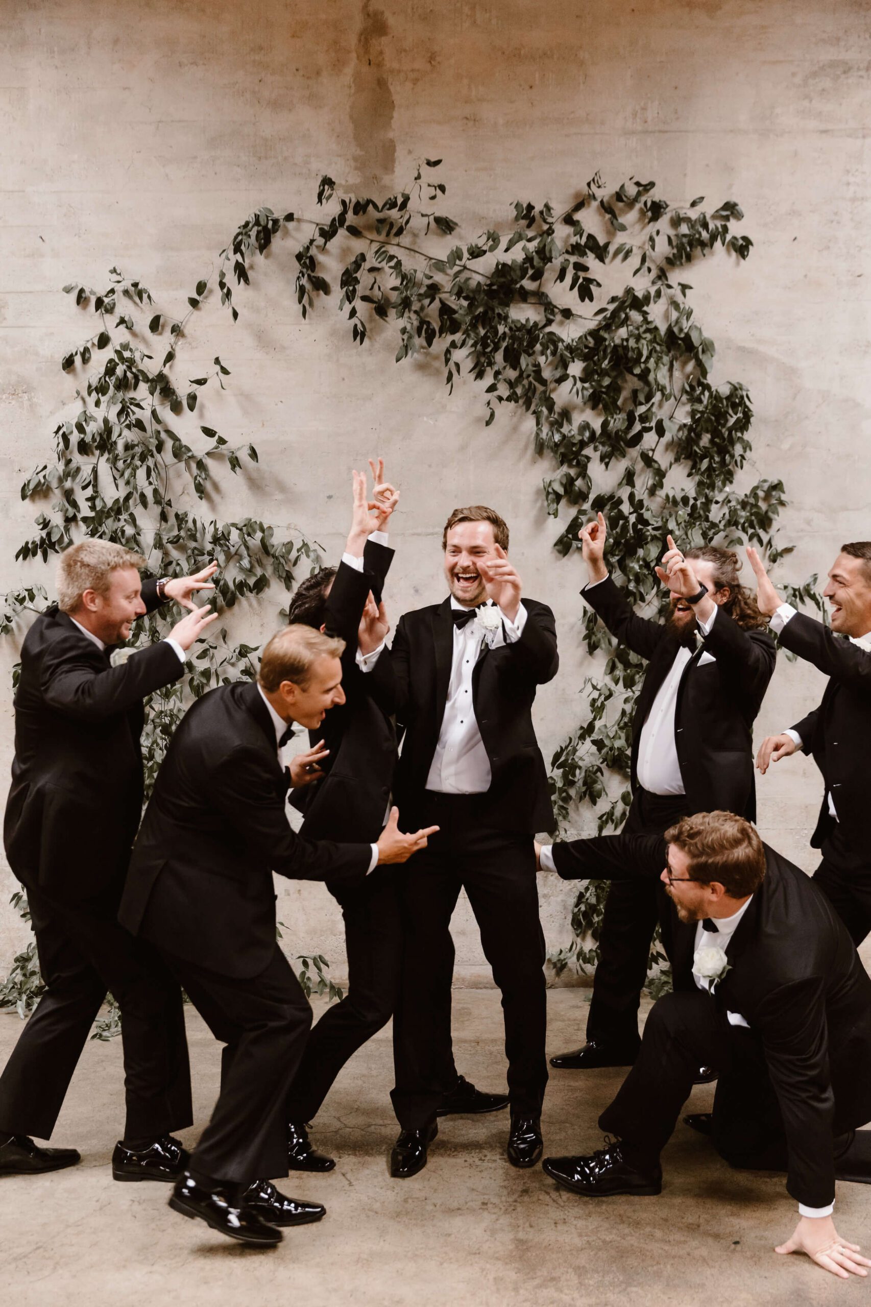 groom and groomsmen celebrating at wedding aisle in black tux suits