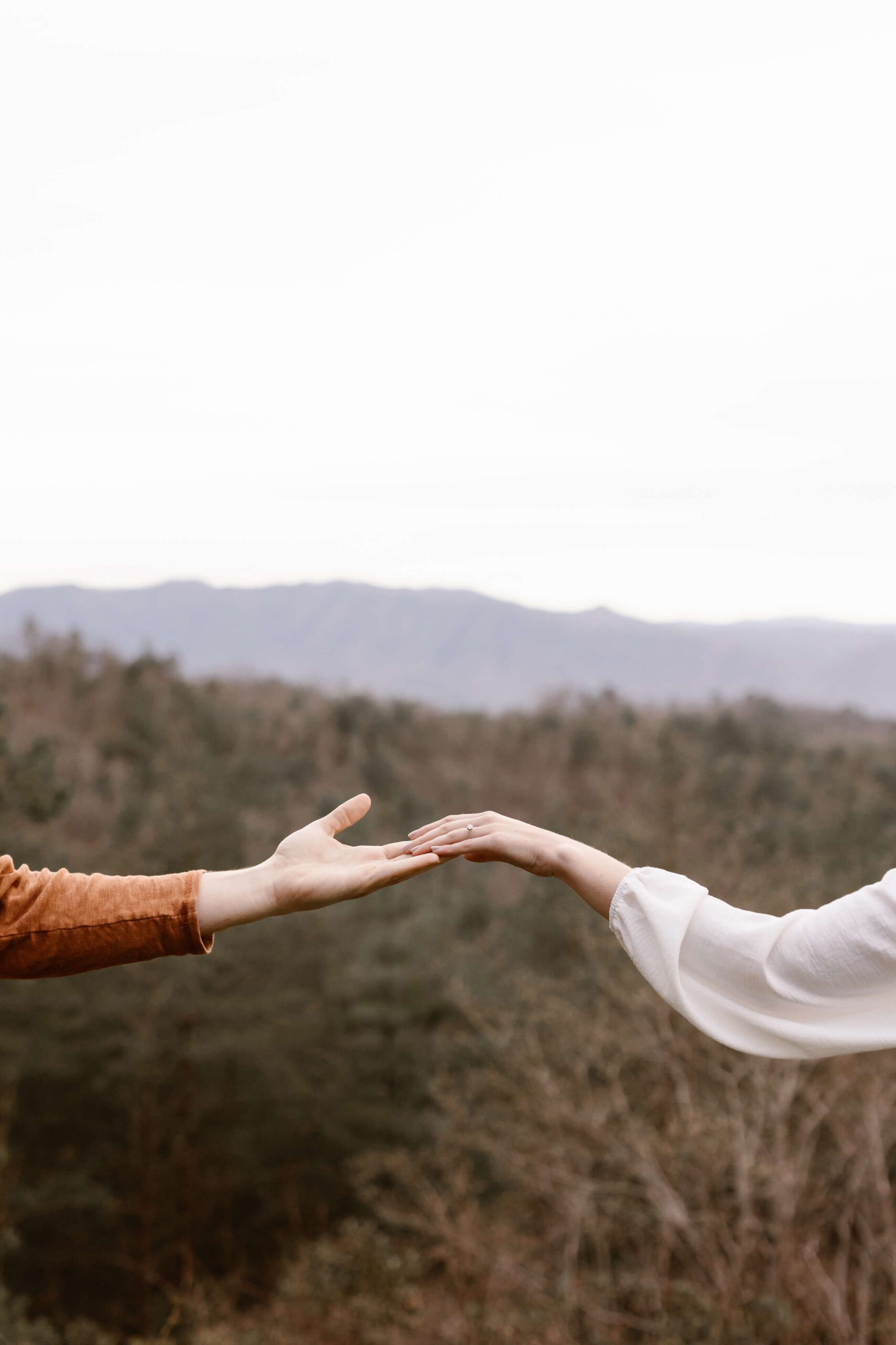 photo of two hands clasping overlooking mountain background by Smoky Mountain Photographer
