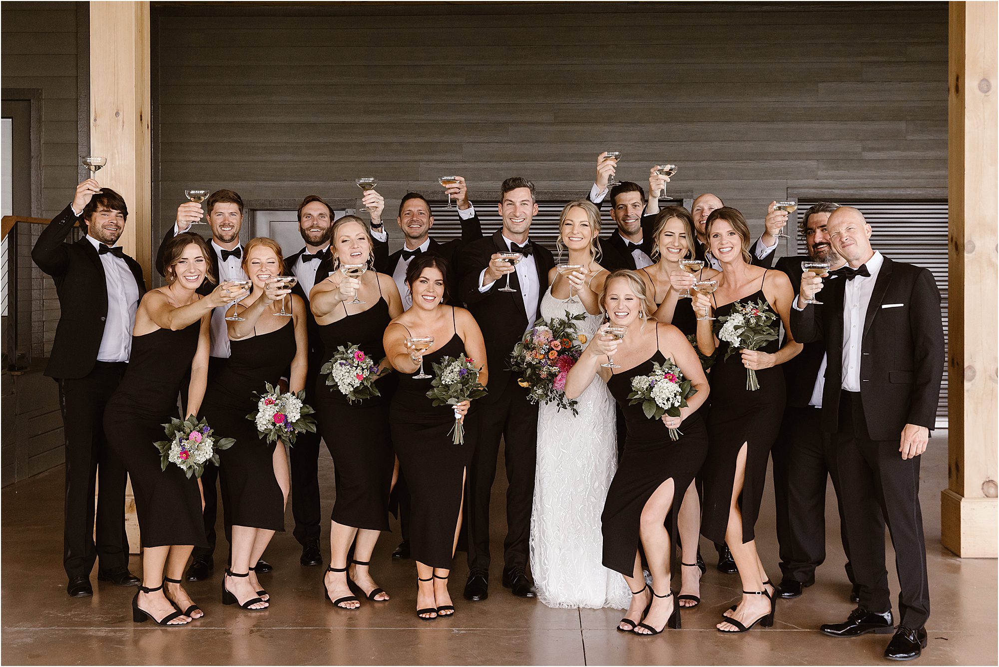 wedding party holding champagne glasses and toasting to bride and groom