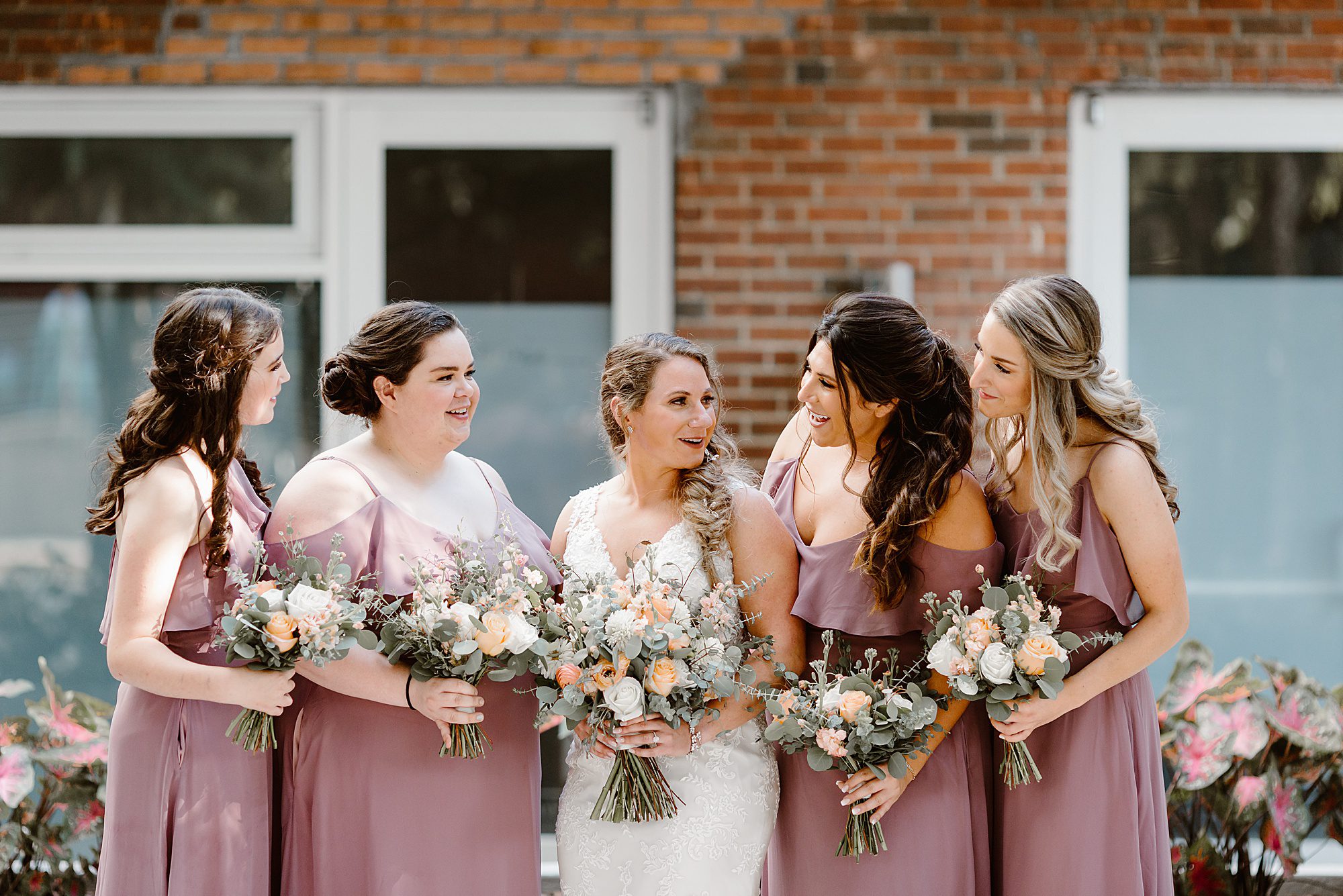 bride laughs with bridesmaids in blush pink dresses