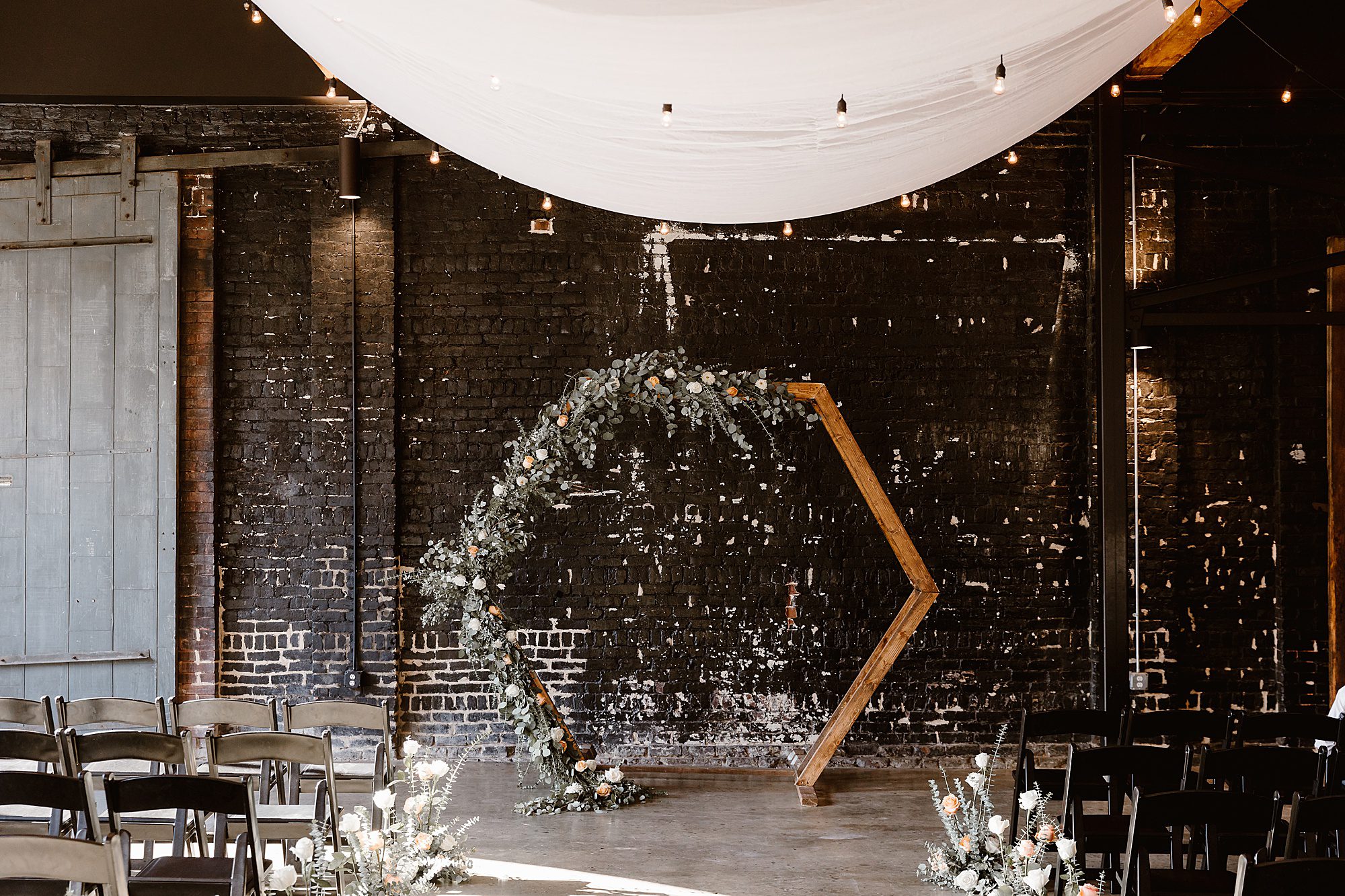 geometric wedding arbor with flowers in black warehouse