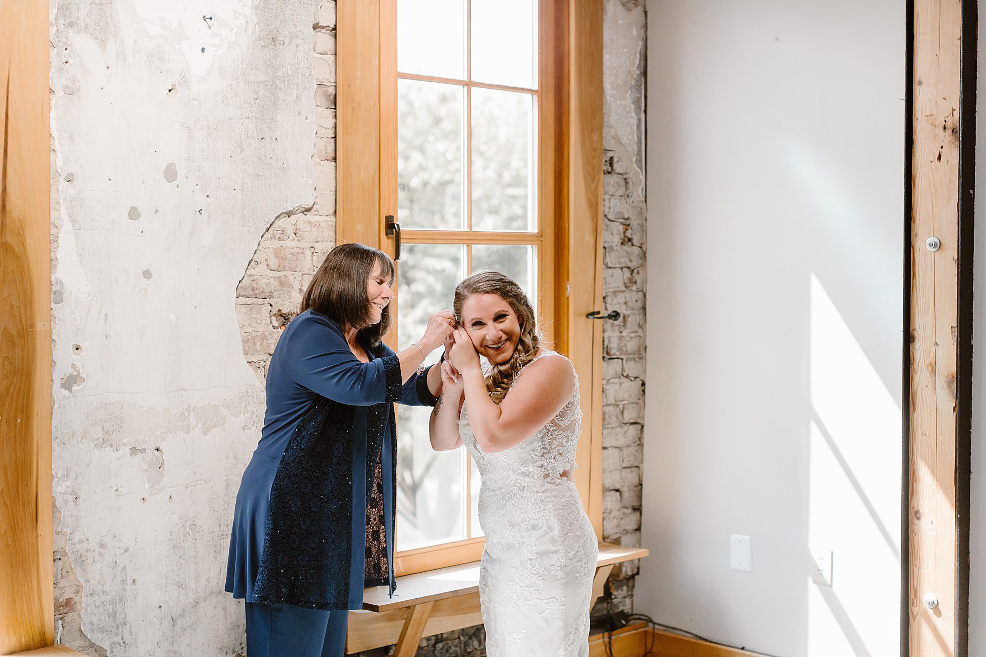 bride and mom putting earrings on while getting ready on wedding day