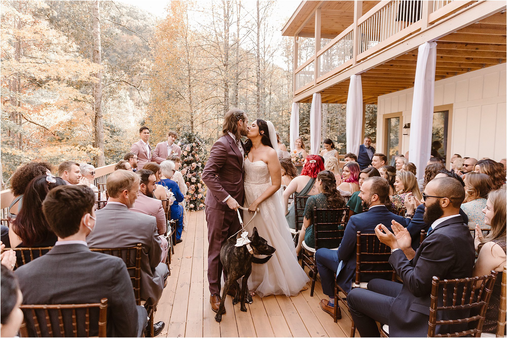 bride and groom walk down ceremony aisle with black dog on cabin deck in Pigeon Forge