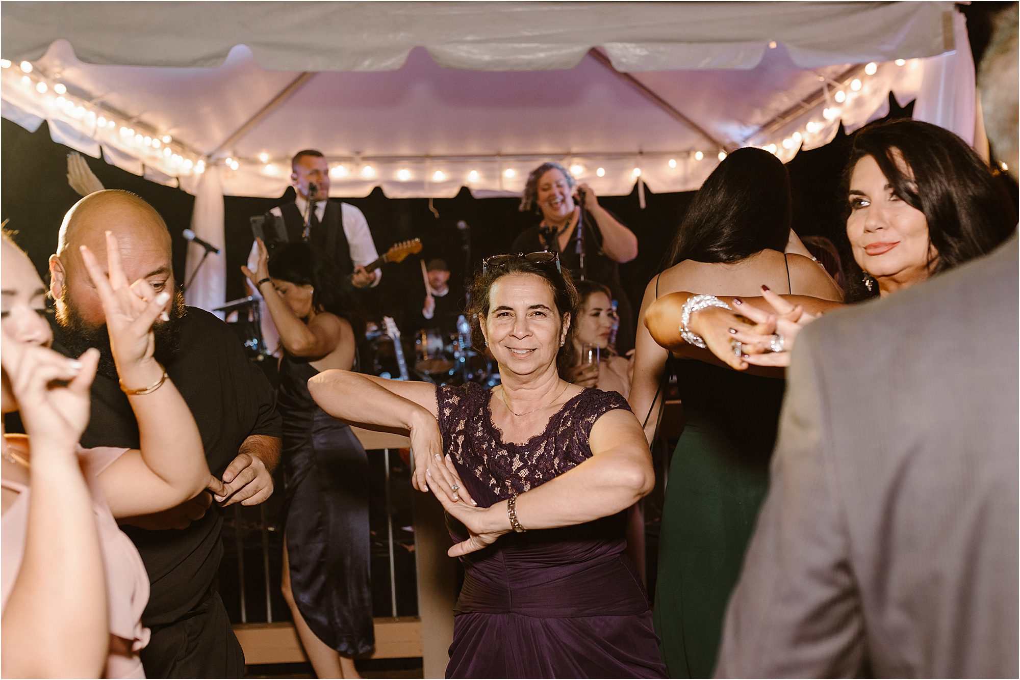 wedding guests dance on dance floor at wedding reception with live band