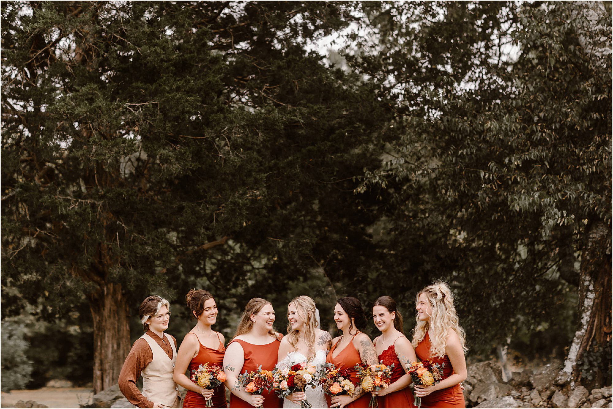 bride standing with bridesmaids in burnt orange bridesmaid dresses
