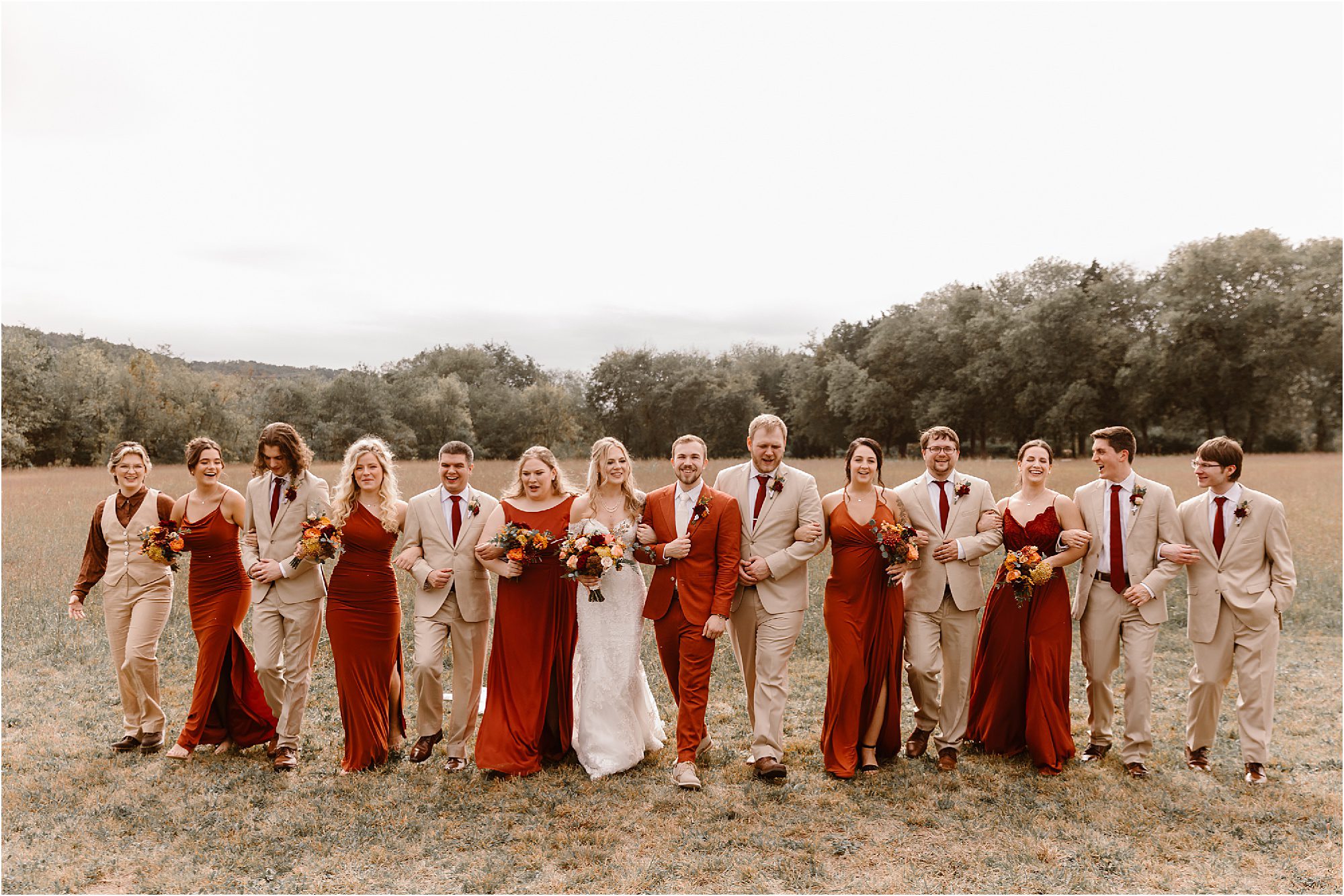 wedding party walking through field in burnt orange and tan wedding colors