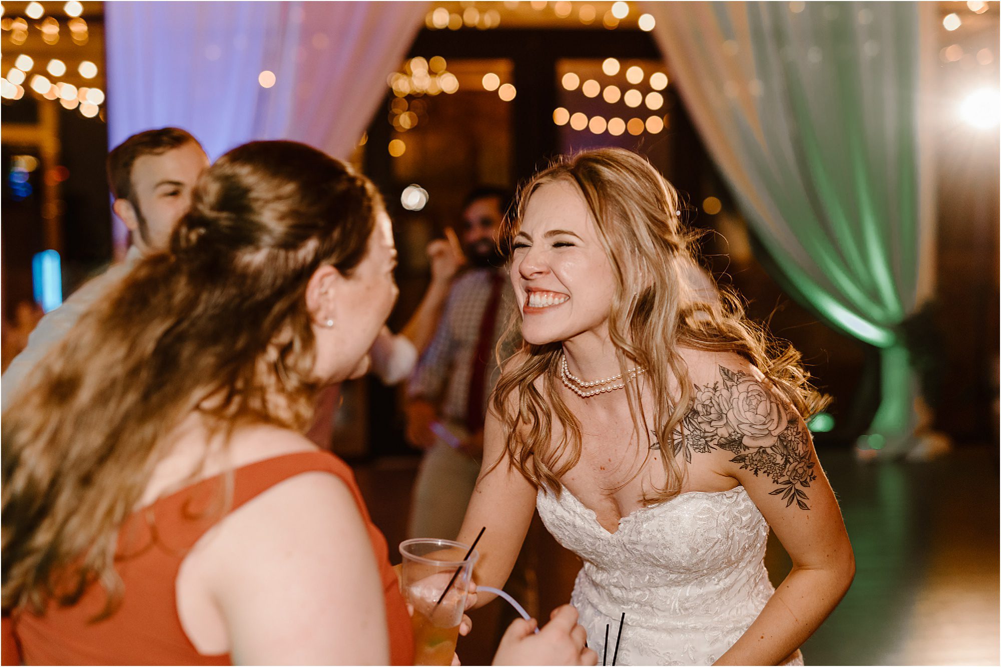 bride smiling and dancing with bridesmaid at wedding