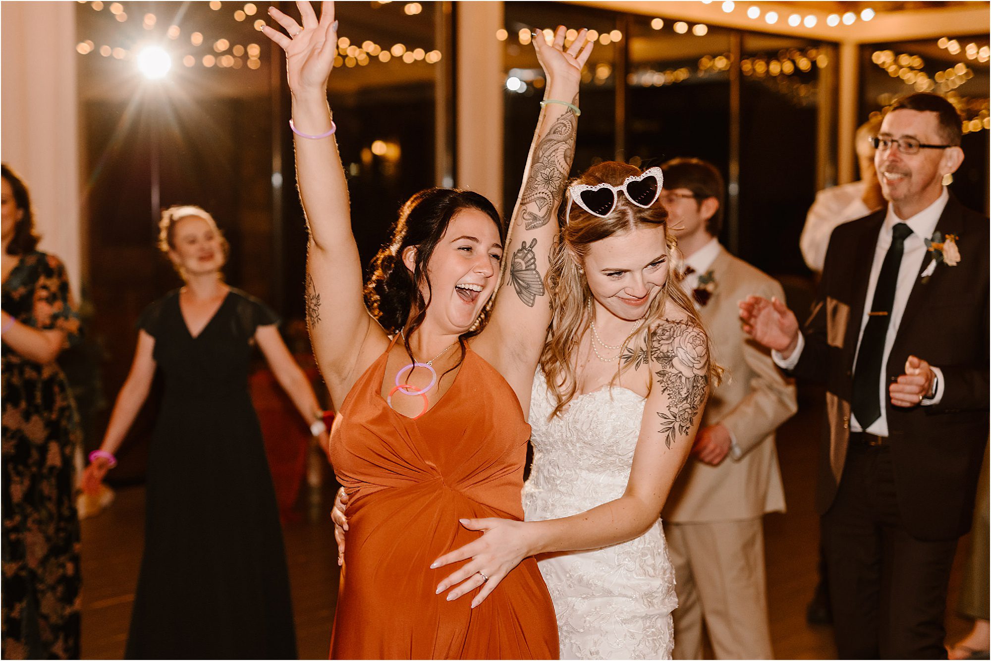 pregnant bridesmaid and bride laughing on dancing floor
