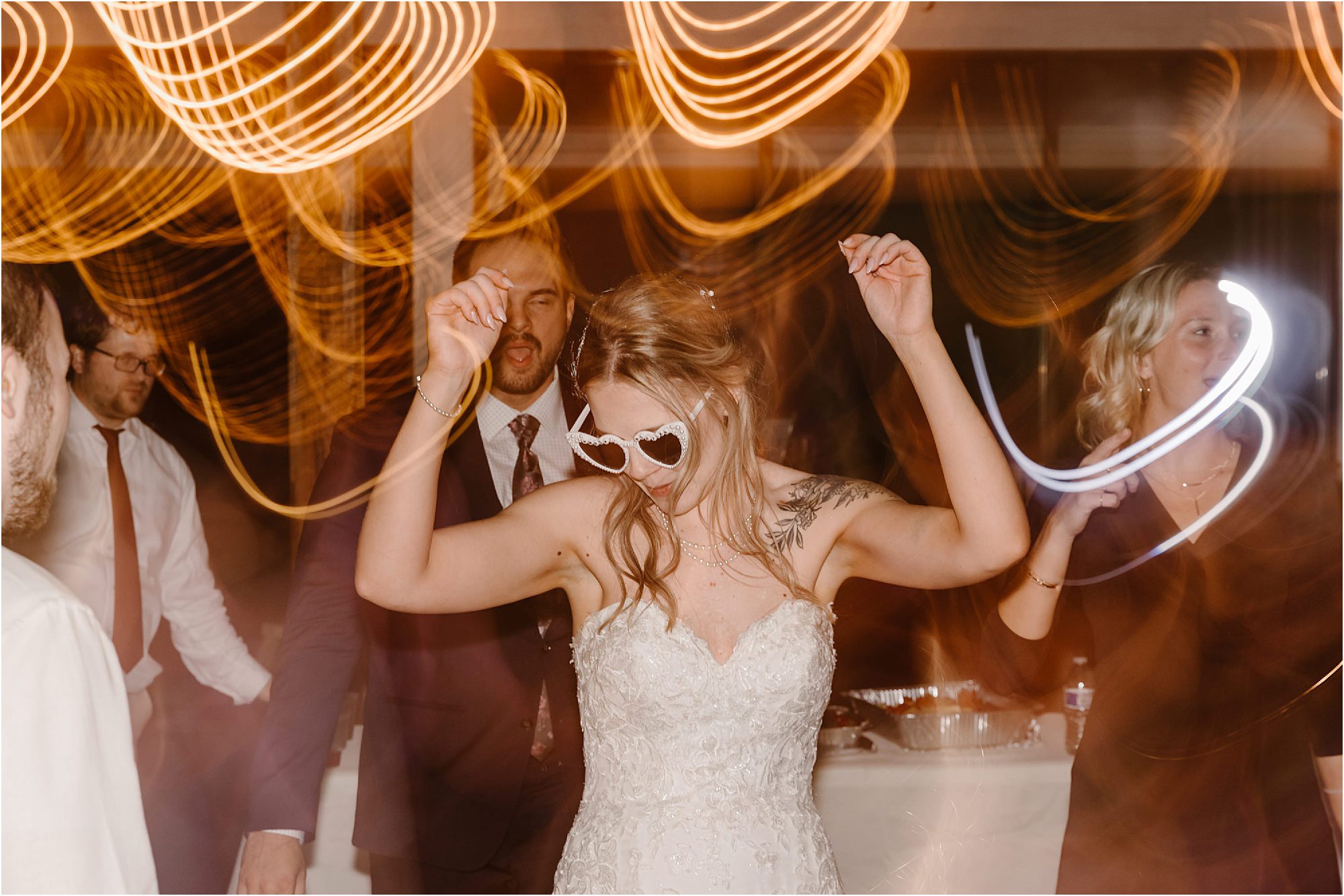 bride in white heart-shaped sunglasses dancing on dance floor at reception