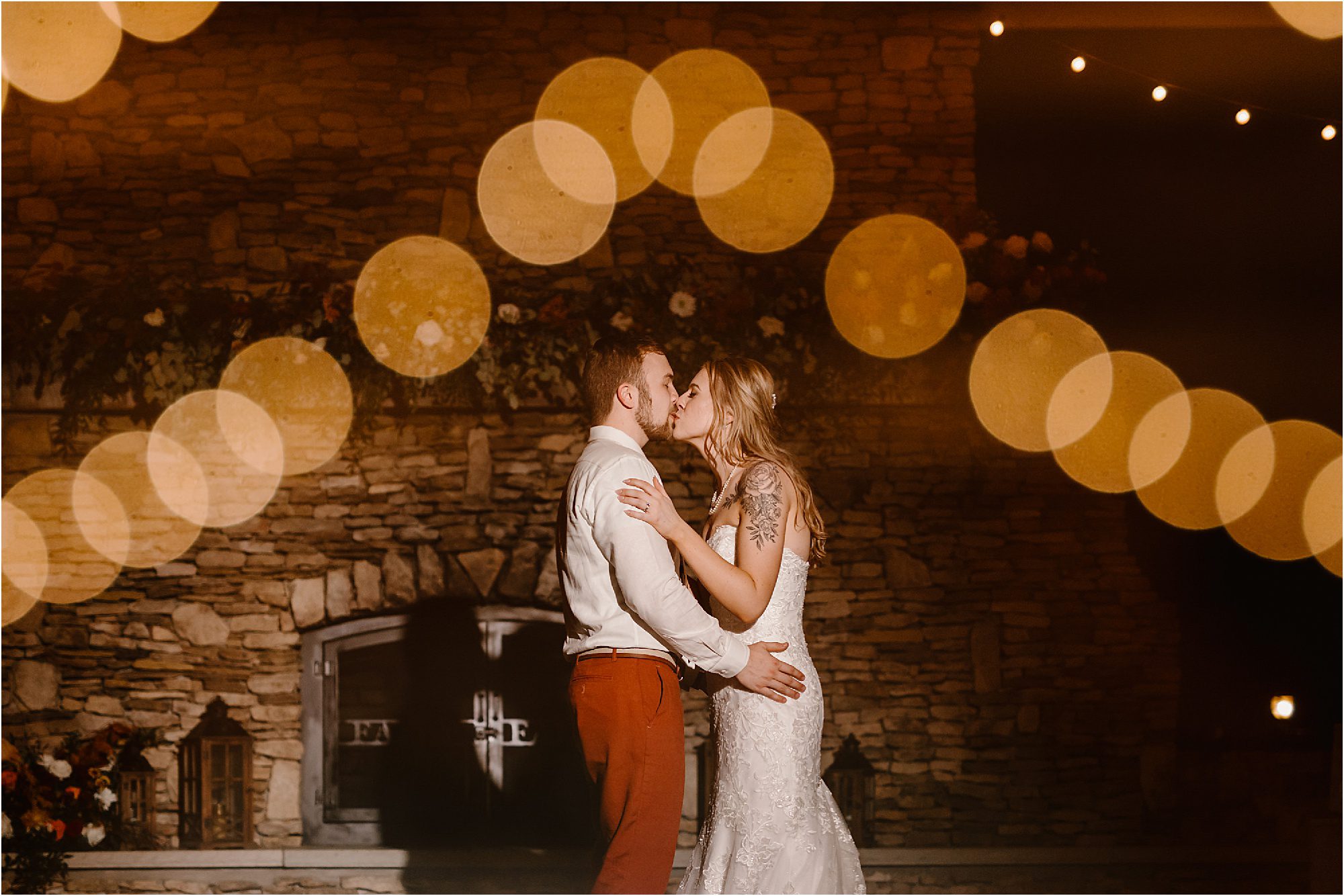 bride and groom kissing in front of fireplace in moody photo