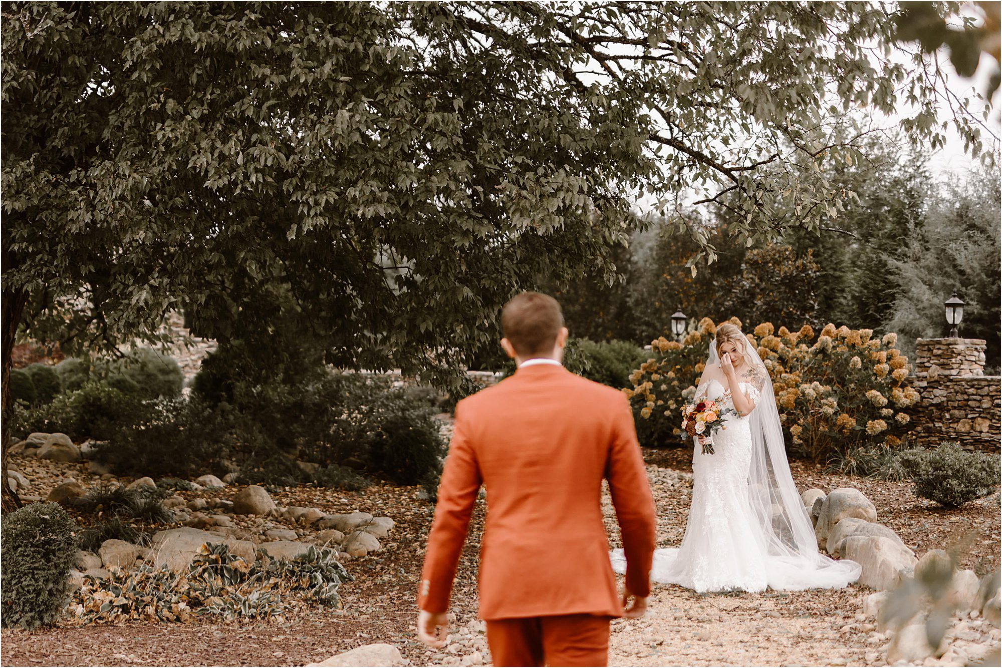 first look with groom in burnt orange suite and bride in sleeveless whtie wedding dress