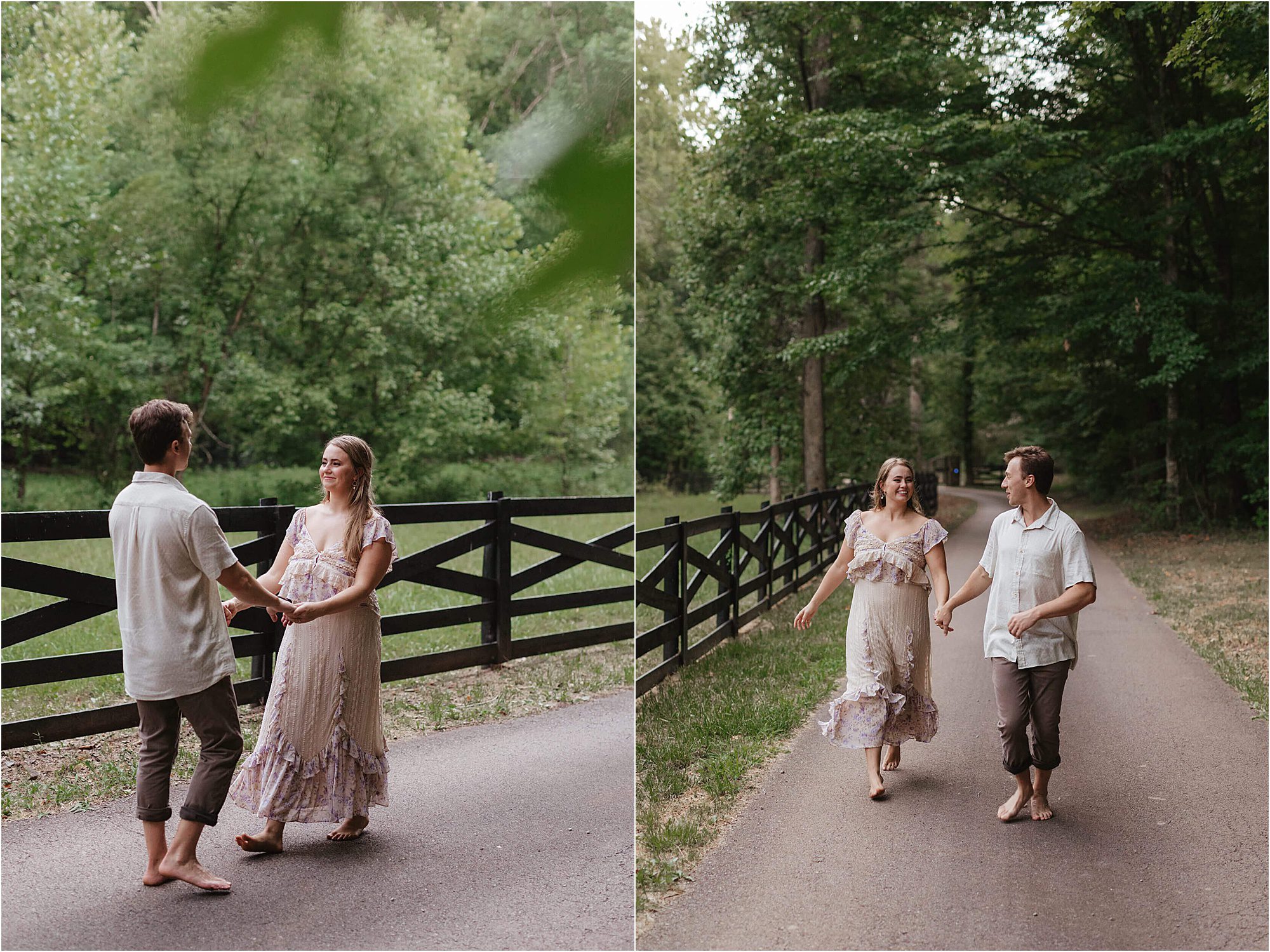 A couple walks barefoot on a paved path by a wooden fence, surrounded by lush green trees during their lakeside engagement session. They hold hands and smile at each other, both dressed in light, casual clothes.